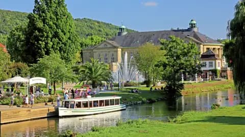 Reisende bei einer Bootsfahrt auf der Fränkischen Saale in Bad Kissingen mit Blick auf den prachtvollen Regentenbau im Kurpark, ein Highlight auf unserer Rundreise mit Studiosus.
