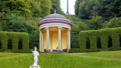Runder Pavillon im barocken Terrassengarten von Kloster Kamp, umgeben von grünen Hecken und mit einem Obelisken im Hintergrund, ein Ausflug auf unserer Gruppenreise mit Studiosus.