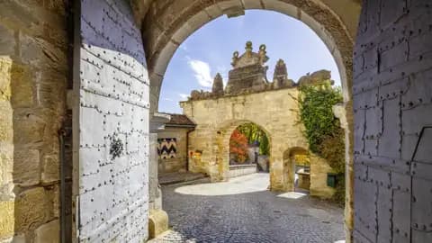Blick durch das geöffnete, eiserne Tor in den sonnigen Innenhof der historischen Veste Coburg, welche Sie während der Studienreise besichtigen werden.