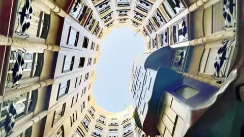 Auf einer Studienreise in Barcelona: Blick nach oben durch den geschwungenen Innenhof von Gaudís Casa Milà zum Himmel.