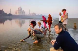 Morgenstimmung am Taj Mahal in Indien, mit Menschen, die am Wasser aktiv sind.