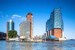 Die Elbphilharmonie und der Hamburger Sandtorhafen vom Wasser aus gesehen an einem sonnigen Tag mit blauem Himmel.