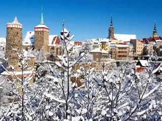 Die Altstadt mit Stadtmauer von Bautzen an einem sonnigen Wintertag mit schneebedeckten Dächern und Bäumen.
