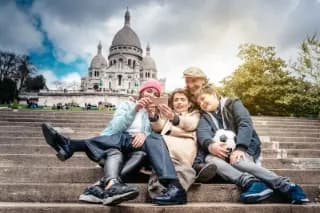 Eine fröhliche Familie macht ein Selfie auf den Stufen vor der Sacré-Cœur-Basilika in Paris.