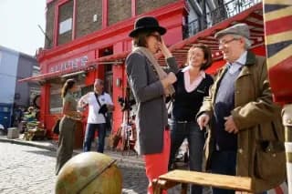 Eine Reisegruppe mit Reiseleiterin besucht einen Flohmarkt in London.