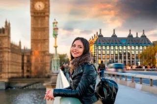Eine junge Frau steht auf der Westminster Brücke in London und lächelt in die Kamera, im Hintergrund der berühmte Big Ben.