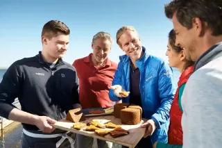 Eine Gruppe von Menschen, die am Strand ein Kuchen teilen und genießen.