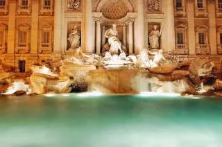 Der Trevi-Brunnen in Rom bei Nacht mit beleuchteten Wasserspielen.