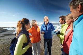 Eine Gruppe von Menschen, die an einem Eisberg in der Natur lachen und sich unterhalten.