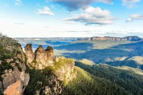 Ein Panoramablick auf die Felsen der Three Sisters in den Blue Mountains in Australien bei sonnigem Wetter.