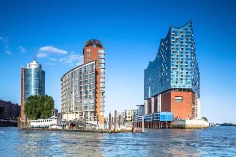 Die Elbphilharmonie und der Hamburger Sandtorhafen vom Wasser aus gesehen an einem sonnigen Tag mit blauem Himmel.