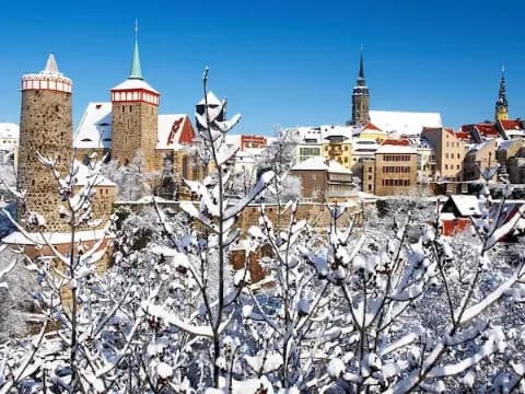 Die Altstadt mit Stadtmauer von Bautzen an einem sonnigen Wintertag mit schneebedeckten Dächern und Bäumen.