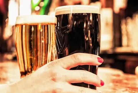 Ein helles und ein dunkles Bier auf einem Holztisch in einem irischen Pub.