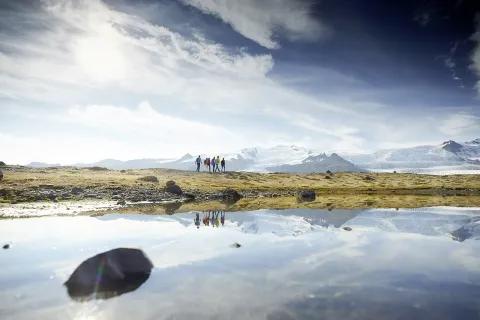 Eine Gruppe von Wanderern in einer isländischen Landschaft mit Bergen und einem klaren Himmel.