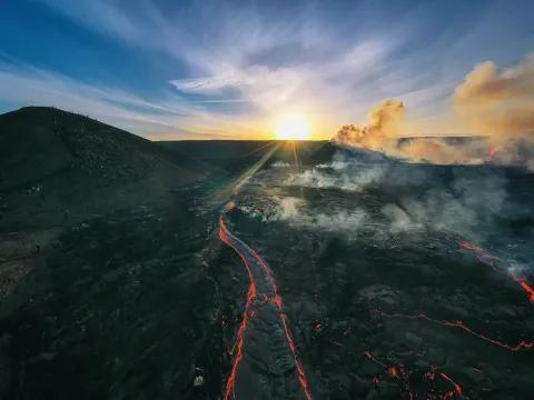 Lavafluss im Vulkan mit rauchenden Wolken und Sonnenstrahlen.