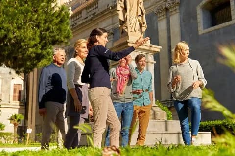 Eine Reisegruppe ist mit einer Reiseleiterin bei sonnigem Wetter unterwegs.