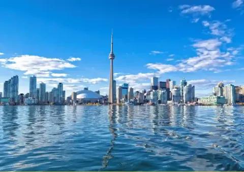 Hochhäuser von Toronto unter leicht bewölktem Himmel und umgeben von Wasser.