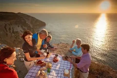 Eine Gruppe von Menschen macht ein Picknick bei Sonnenuntergang am Meer.