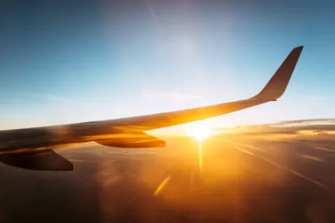 Blick auf einen Flugzeugflügel, den Himmel und die Wolken von einem Flugzeug aus.