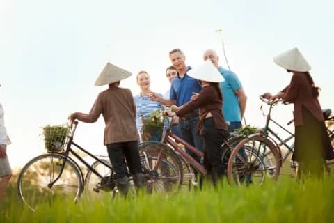 Eine Gruppe von Menschen, die in einem Feld mit Fahrrädern stehen.