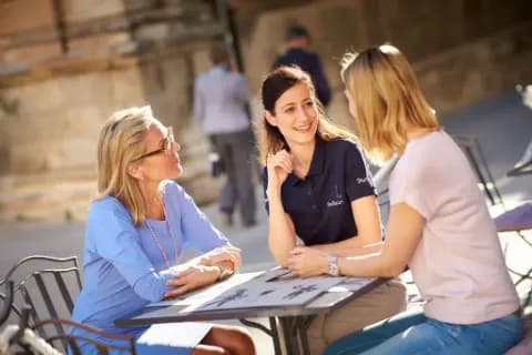 Reiseleiterin spricht im Café mit zwei Frauen.