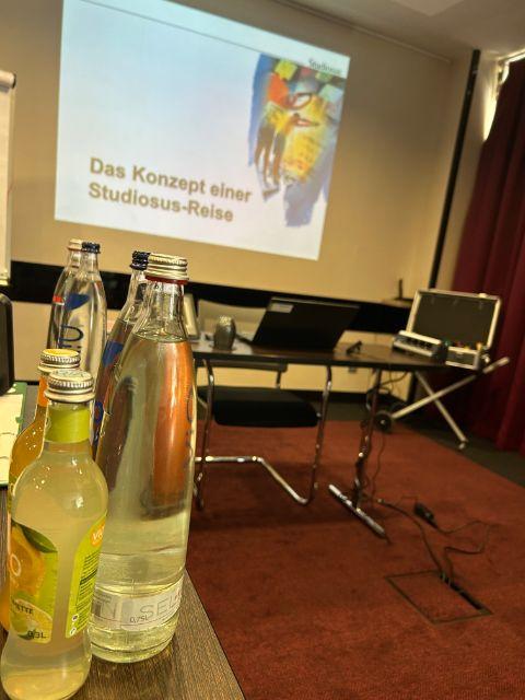 Live Bild eines unserer Seminare "Reiseleitung bei Studiosus": Getränke vor der Beamer Projektion auf der steht: "Das Konzept einer Studiosus-Reise"