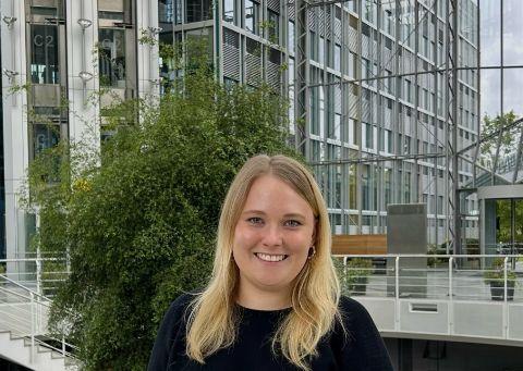 Eine Frau mit blonden Haaren steht in einem Glasgebäude.