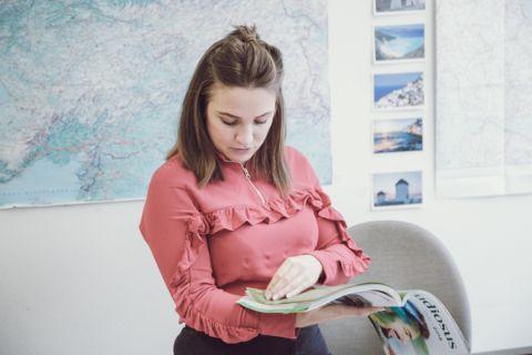 Ein Büro mit einer Weltkarte im Hintergrund und einer Frau, die ein Magazin durchblättert.