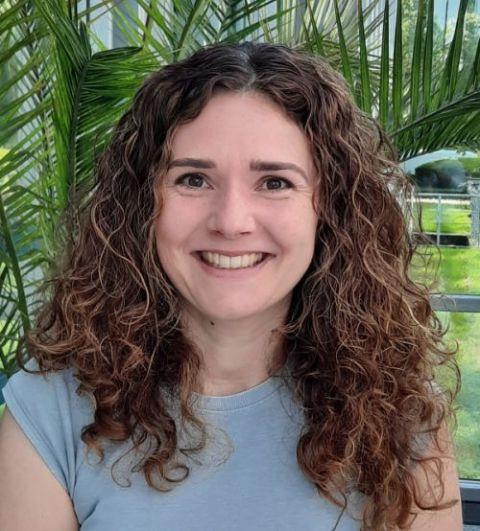Portrait einer Frau mit lockigem Haar und natürlichem Hintergrund.
