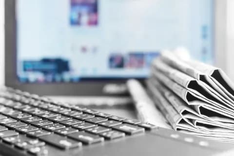 Nahaufnahme einer Tastatur und eines Zeitungsstapels.