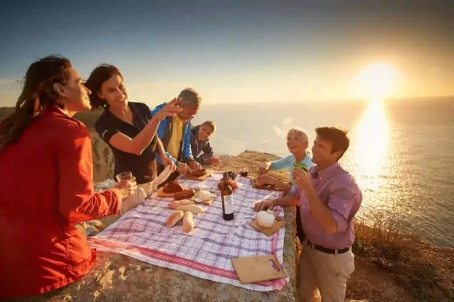 Eine Gruppe von Freunden genießt ein Picknick am Meer bei Sonnenuntergang.
