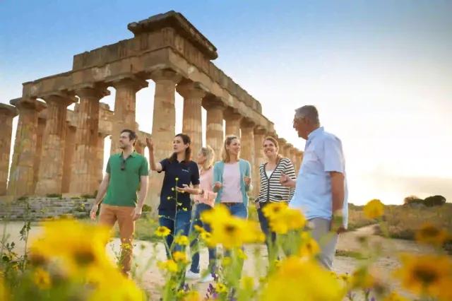 Eine Gruppe von Touristen, die vor antiken Säulen stehen und sich unterhalten.