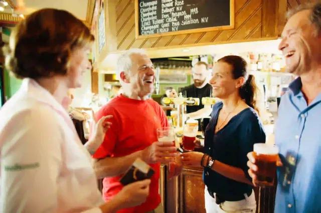 Eine gesellige Runde von Freunden in einem Pub, die Bier genießen und lachen.