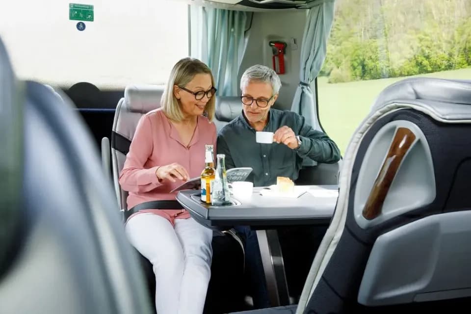 Ein freundliches Paar genießt eine Reise in einem Reisebus mit Getränken und Snacks.