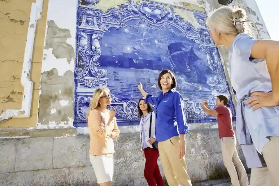 Eine Gruppe von Frauen, die ein blaues Mosaik an einer Wand in Lissabon bewundern.
