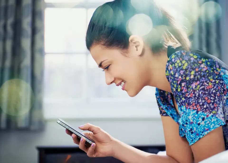 Eine junge Frau liest etwas auf ihrem Handy.