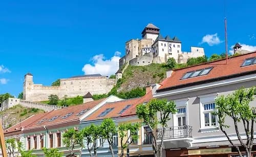 Einige Häuser in der Altstadt der slowakischen Stadt Trencin sind zu sehen, über der die weiße Burg trohnt.