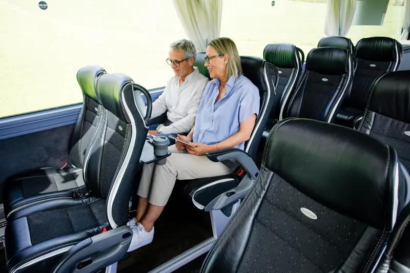 Zwei Personen genießen eine entspannte Fahrt in einem modernen Reisebus.