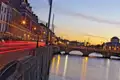 Dublin bei Sonnenuntergang mit Blick auf den Fluss Liffey und die O'Connell Street. Das Bild zeigt die Lichter der Stadt und den Fluss, der im Abendlicht glitzert.