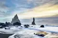 Die markanten Felsnadeln Reynisdranga am schwarzen Sandstrand von Reynisfjara. Bei dieser Reise ist dies ein im Reiseverlauf geplanter Stopp an Islands Südküste.