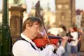 Ein Straßenmusiker spielt Geige auf der Karlsbrücke, ein typisches Erlebnis während der Stadterkundung in Prag.