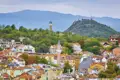 Blick über die Altstadt von Plovdiv während eines Stadtrundgangs, mit traditionellen Häusern,dem Minarett der Dschumaja-Moschee und einem der charakteristischen grünen Hügel der Stadt im Hintergrund.