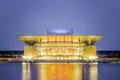 Das beleuchtete Opernhaus Kopenhagen bei Nacht, dessen Lichter sich im Wasser spiegeln.