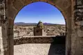 Auf unserer Gruppenreise mit Studiosus bewundern wir den Panoramablick von der Burg Trujillo durch einen Steinbogen auf die historische Altstadt mit ihren Türmen unter einem blauen Himmel in der Extremadura.