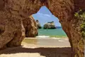 Auf unserer Gruppenreise mit Studiosus werfen wir einen Blick durch ein Felsentor auf den Atlantik an der Algarve, eine Felsformation am Praia dos Três Irmãos, einem  malerischem Strandabschnitt im Osten von Alvor, Algarve, Portugal.