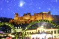 Auf unserer Silvesterreise besuchen wir den Weihnachtsmarkt in Heidelberg mit Buden und Lichtern vor der beleuchteten Burg im Schnee.