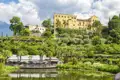 Die Gärten von Schloss Trauttmannsdorff bei Meran in Südtirol mit mediterraner Vegetation, See und dem historischen Schloss, ein Highlight unserer Gruppenreise mit Studiosus nach Südtirol.