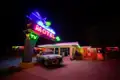 Ikonisches Neon-Schild des Blue Swallow Motels an der Route 66 in Tucumcari erhellt nachts einen Oldtimer, ein Highlight unserer Gruppenreise mit Studiosus.