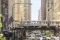 Die ikonische Hochbahn 'The L' in Chicago fährt über eine Brücke in einer belebten Straßenschlucht mit viel Verkehr, ein toller Anblick auf unserer Studiosus Rundreise durch die USA.