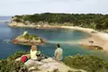 Zwei Reisende einer Studienreise genießen von einer Klippe den Ausblick auf die malerische Portelet Bay auf Jersey.
